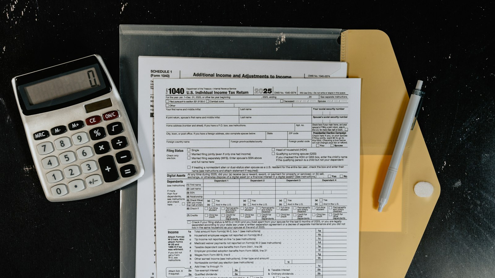 A calculator, pen and printed tax forms in a folder on a dark surface