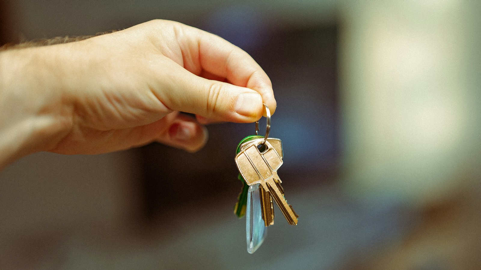 A hand holding up a small bunch of keys against a blurred background