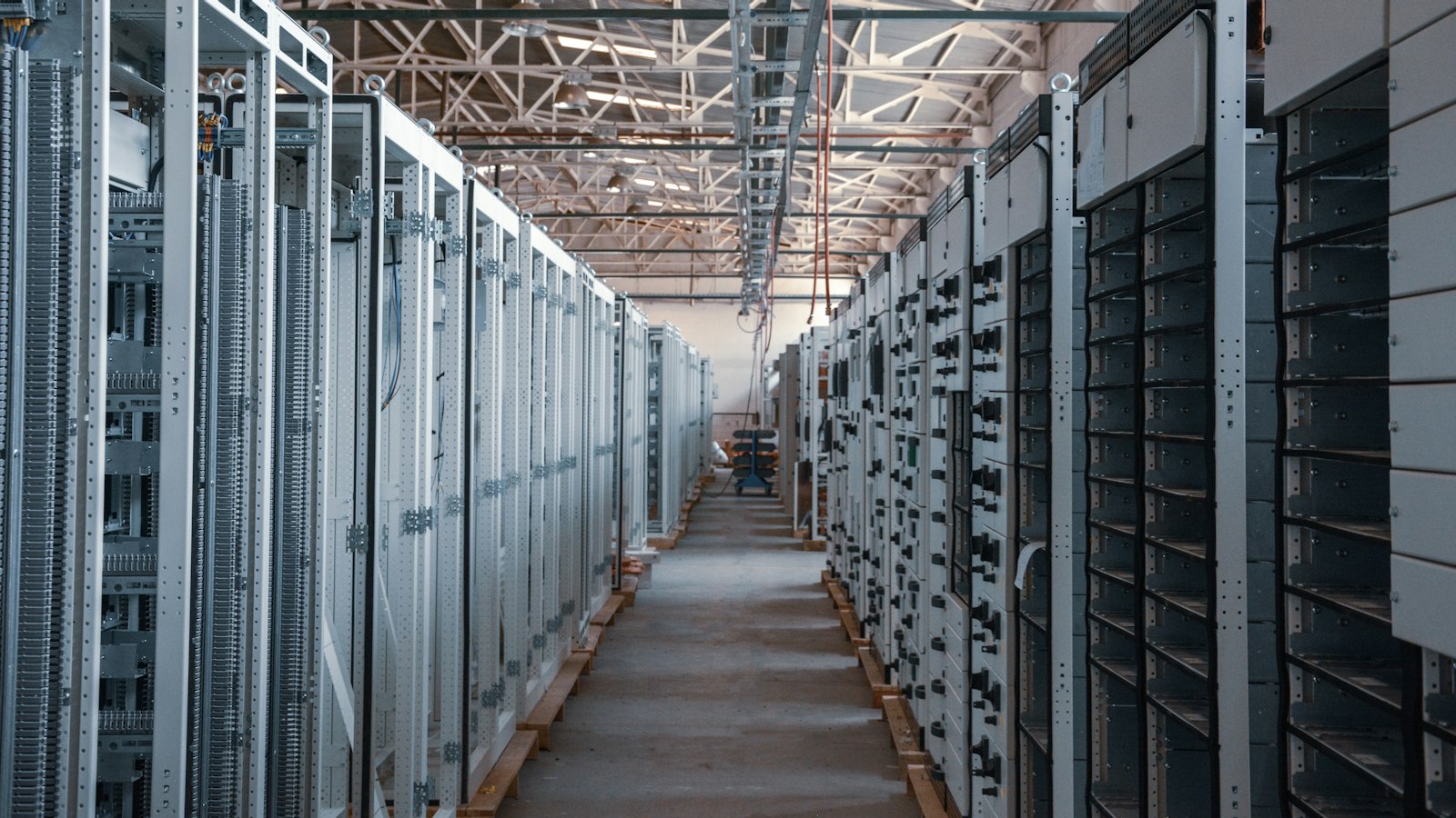 Narrow aisle between tall metal equipment cabinets in an industrial server room