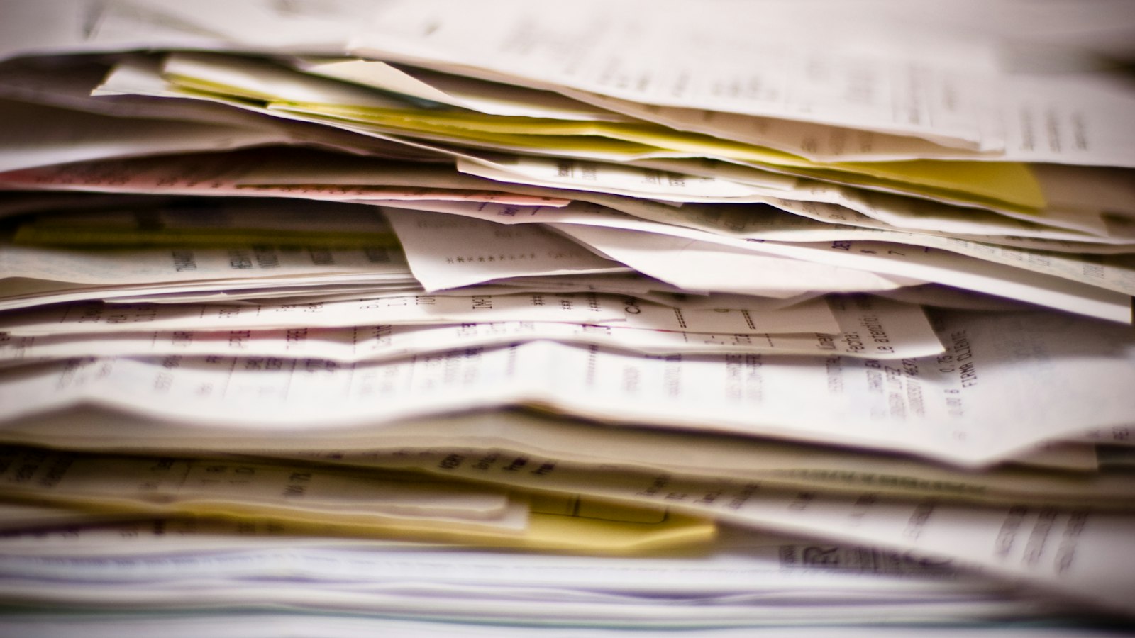 Thick stack of invoices and receipts piled up on a desk
