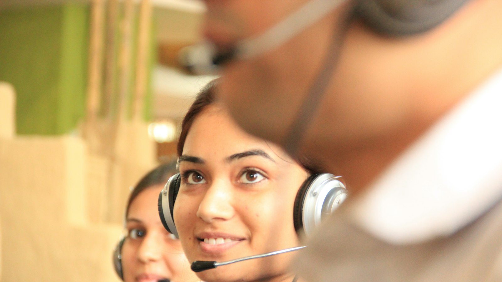 Two smiling call center agents wearing headsets at their workstations