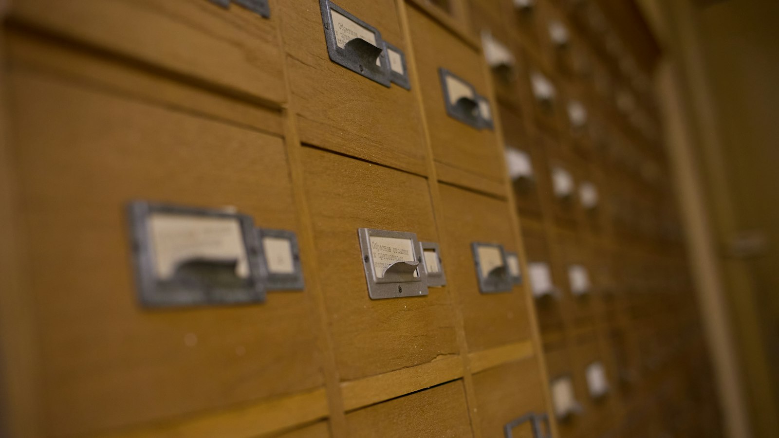 Rows of wooden card catalog drawers with small metal label holders