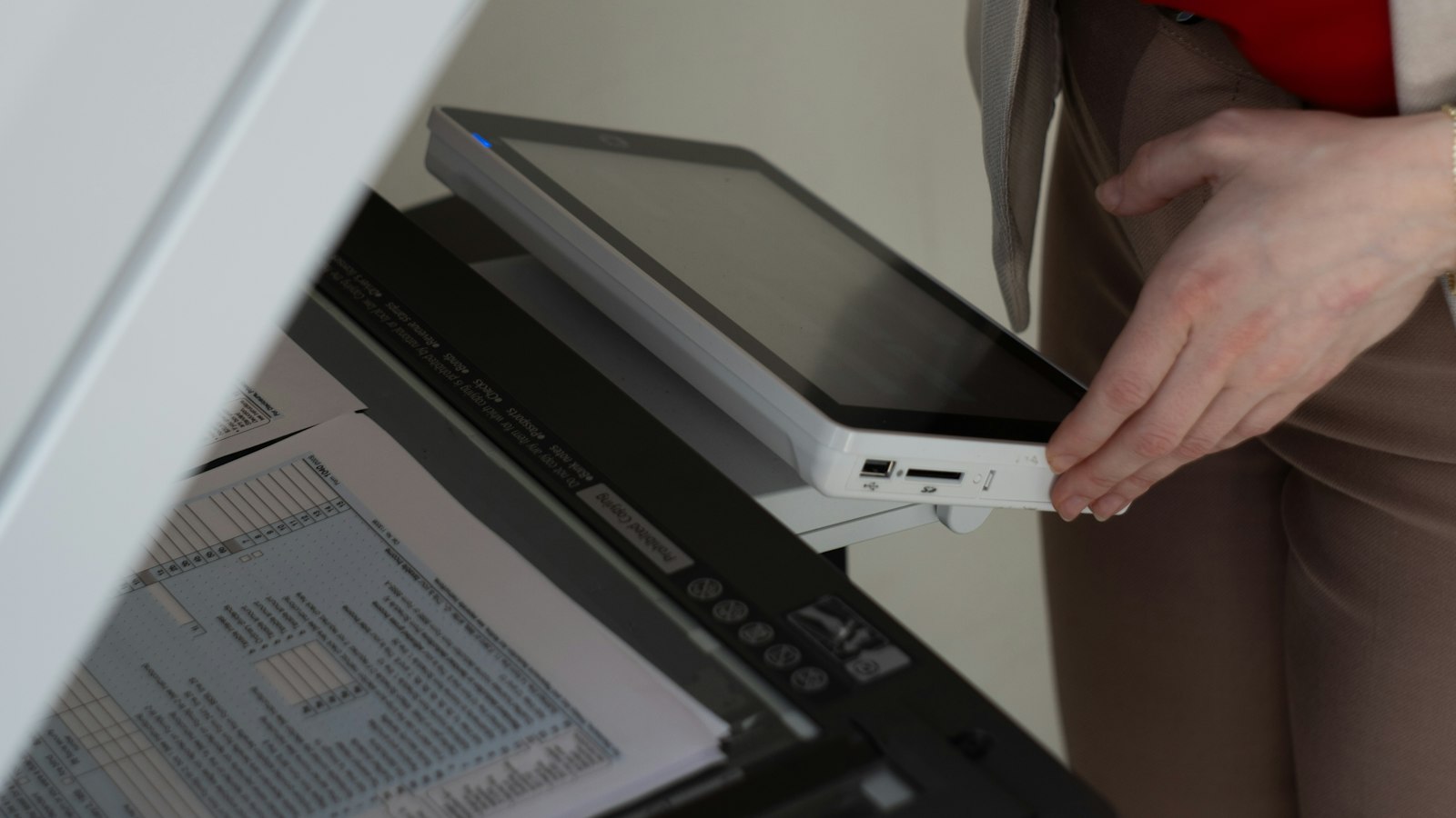 Hand inserting a document into an office scanner feeder with a tablet panel