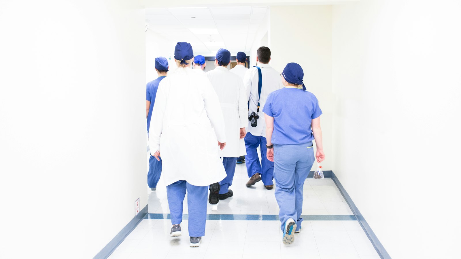 Group of doctors and nurses in scrubs walking down a bright hospital hallway