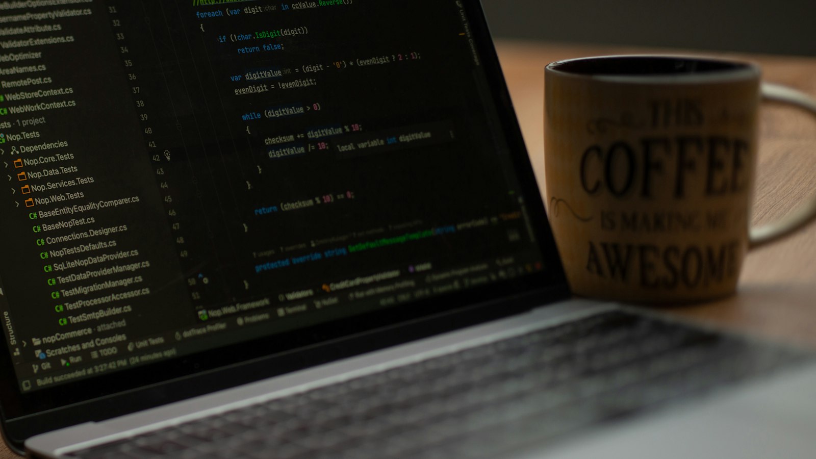 Laptop screen showing lines of code next to a coffee mug on a desk