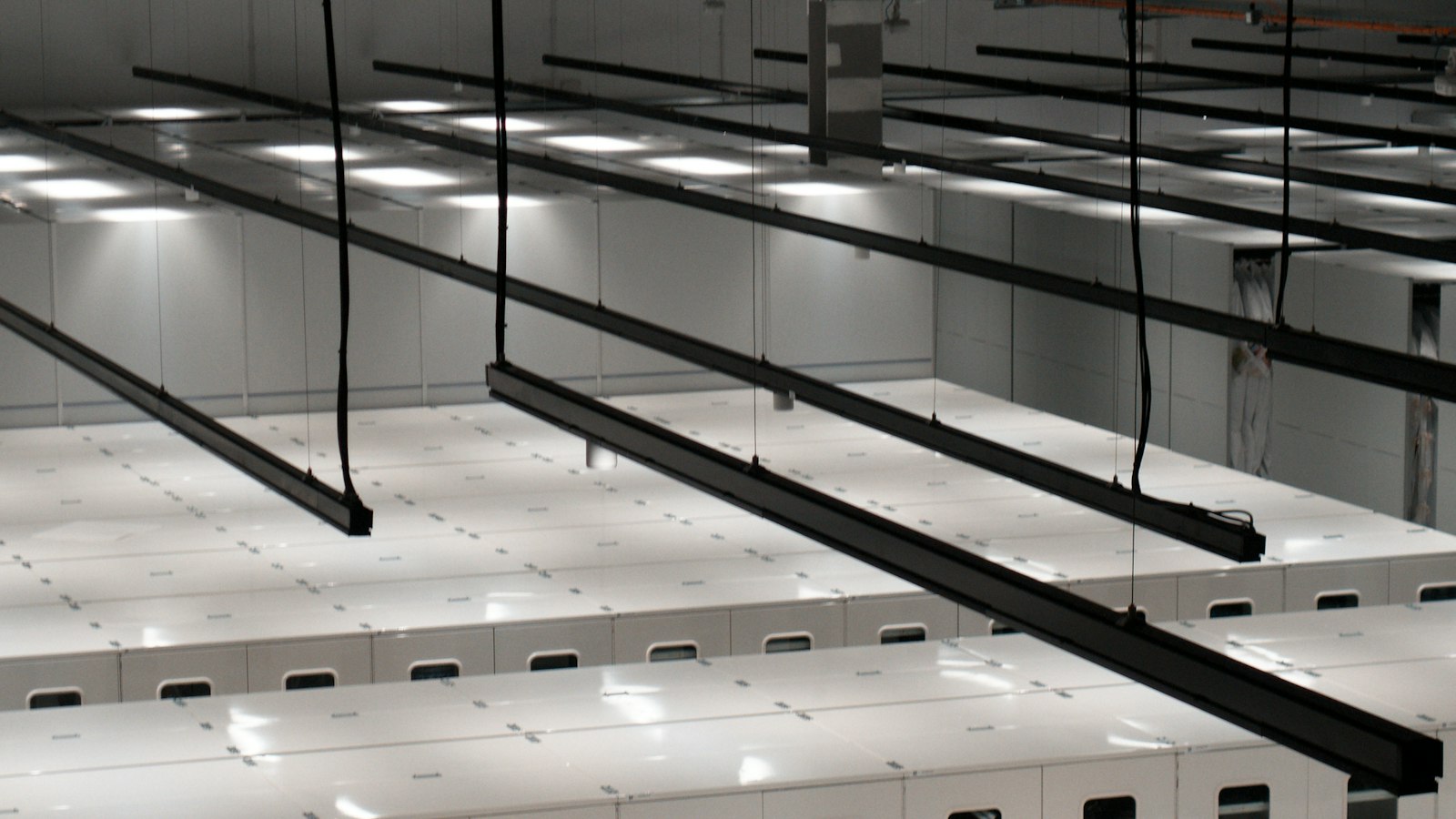 Rows of white server cabinets lit by ceiling lights in a data center